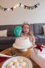 Kleines Mädchen bläst zu Hause die Kerzen auf ihrem Geburtstagskuchen aus — Stockfoto