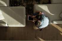 Вид сверху на отца и дочь с помощью цифрового планшета дома — стоковое фото
