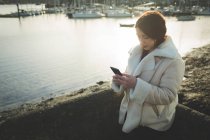 Жінка використовує мобільний телефон біля річки біля води . — стокове фото
