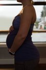 Средняя часть беременной женщины прикасается к животу дома — стоковое фото