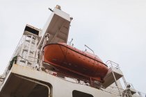 Visão de baixo ângulo do barco de resgate e um bote salva-vidas pendurado em um lado de um navio — Fotografia de Stock