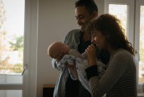 Eltern halten ihr Baby zu Hause im Wohnzimmer — Stockfoto