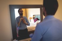 Empresário que se veste em frente ao espelho no quarto de hotel — Fotografia de Stock
