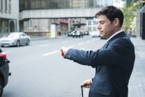 Бизнесмен проверяет время на наручных часах на улице — стоковое фото