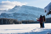 Couple of backpackers looking at map in snowy landscape during winter. — Stock Photo