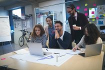 Lächelnde Führungskräfte diskutieren über Laptop im modernen Büro — Stockfoto
