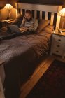 Mann liegt im Bett und telefoniert mit Laptop zu Hause — Stockfoto