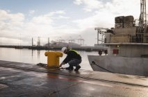 Trabajador portuario atando cuerda en pilona en el astillero - foto de stock