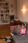 Fille en utilisant un ordinateur portable sur le canapé dans le salon à la maison — Photo de stock