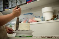 Primer plano de la mujer que prepara el pastel en la panadería - foto de stock