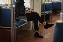 Жінка з ногами, схрещеними за допомогою цифрового планшета під час подорожі в поїзді — стокове фото