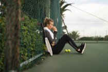 Jeune femme prenant un café au court de tennis — Photo de stock