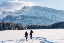 Coppia di passeggiate con racchette da sci insieme nel paesaggio innevato durante l'inverno . — Foto stock