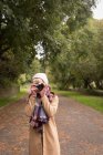 Donna che scatta foto con fotocamera vintage nel parco — Foto stock