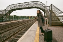 Жінка чекає на поїзд з багажем на залізничній платформі — стокове фото