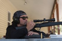 Людина прицілює снайперську гвинтівку на ціль у полігоні на сонячний день — стокове фото