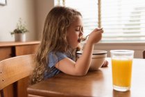 Mädchen beim Frühstück Müsli und Saft auf dem Tisch zu Hause — Stockfoto