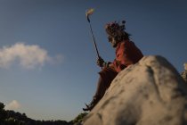 Масаи в традиционной одежде сидит на скале в сельской местности — стоковое фото