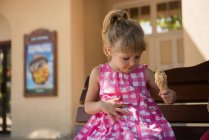 Девушка смотрит на капли растаявшего мороженого, падающие на платье — стоковое фото