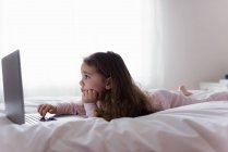 Kleines Mädchen benutzt Laptop im Schlafzimmer zu Hause — Stockfoto
