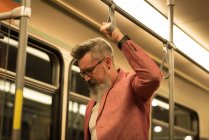 Mann steht mit Unterstützung von Zuggriff im Zug — Stockfoto