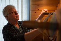 Активная пожилая женщина плетет шелк в магазине — стоковое фото