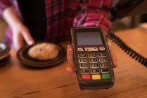 Mid section of woman holding payment terminal at counter in cafe — Stock Photo