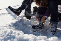 Vue recadrée de l'homme et de la femme portant des patins dans la neige . — Photo de stock
