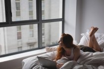 Donna che utilizza il computer portatile in camera da letto a casa — Foto stock