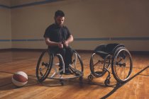 Homem com deficiência ajustando cinto de cadeira de rodas no tribunal — Fotografia de Stock