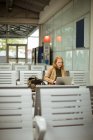Young woman using her laptop at bus stop — Stock Photo
