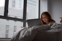 Woman using laptop in bedroom at home — Stock Photo