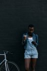 Frau beim Kaffeetrinken mit Handy gegen Wand — Stockfoto