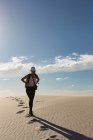 Female hiker with backpack walking on sand on a sunny day — Stock Photo