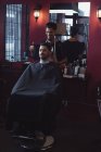 Hombre mirando su nuevo corte de pelo en el espejo en la barbería - foto de stock