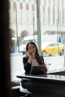 Бізнес-леді розмовляємо по телефону під час користування свого планшетний в кафетерії — стокове фото