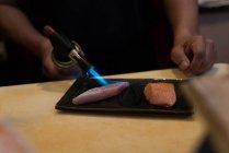 Chef cooking fish slice with a blow torch in a restaurant — Stock Photo