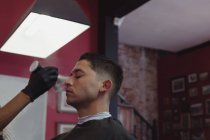Barber cleaning customer face with brush at barbershop — Stock Photo