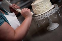 Primer plano de la mujer que prepara el pastel en la panadería - foto de stock