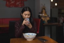 Junge Frau trinkt grünen Tee im Restaurant — Stockfoto