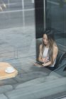 Азіатський бізнес-леді сидячи поодинці за допомогою її планшетного ПК у фойє — стокове фото