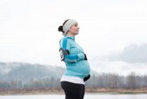 Vista lateral da mulher grávida tocando sua barriga no parque — Fotografia de Stock