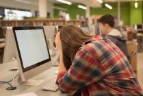 Adolescente cansada sentada en clase de informática en la universidad - foto de stock