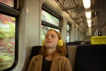 Young woman relaxing while listing to music in train — Stock Photo