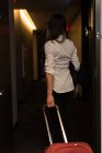 Rückansicht einer Geschäftsfrau, die mit Gepäck aus dem Hotelzimmer geht — Stockfoto