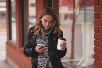 Девочка, пользующаяся мобильным телефоном во время кофе вне дома — стоковое фото
