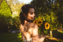 Schöne Braut, die einen Sonnenblumenstrauß im Garten riecht — Stockfoto