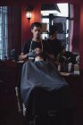 Парикмахер наносит крем на бороду клиентов в парикмахерской — стоковое фото