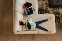 Overhead view of siblings with headphones using digital tablet at home — Stock Photo