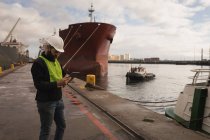 Trabajador portuario utilizando tableta digital en el astillero - foto de stock